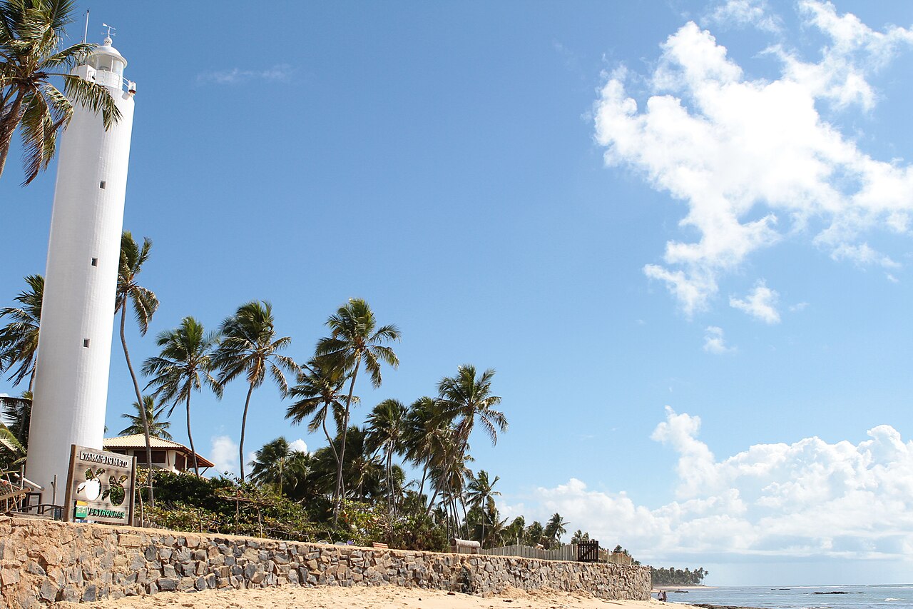 White lighthouse and palms beside the sea in Praia do Forte