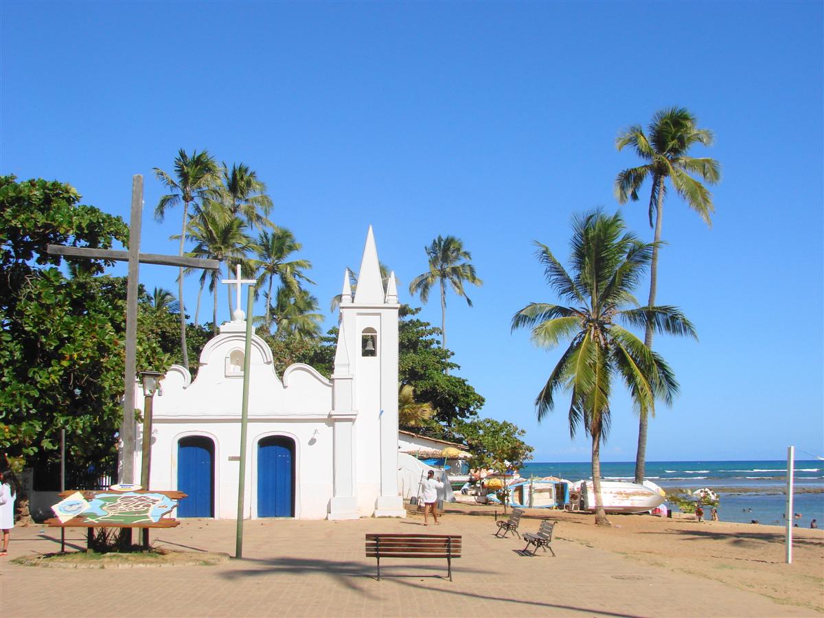 White church and palm trees beside the beach in Praia do Forte